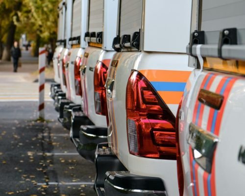A row of pick-up trucks parked outdoors during autumn with falling leaves.